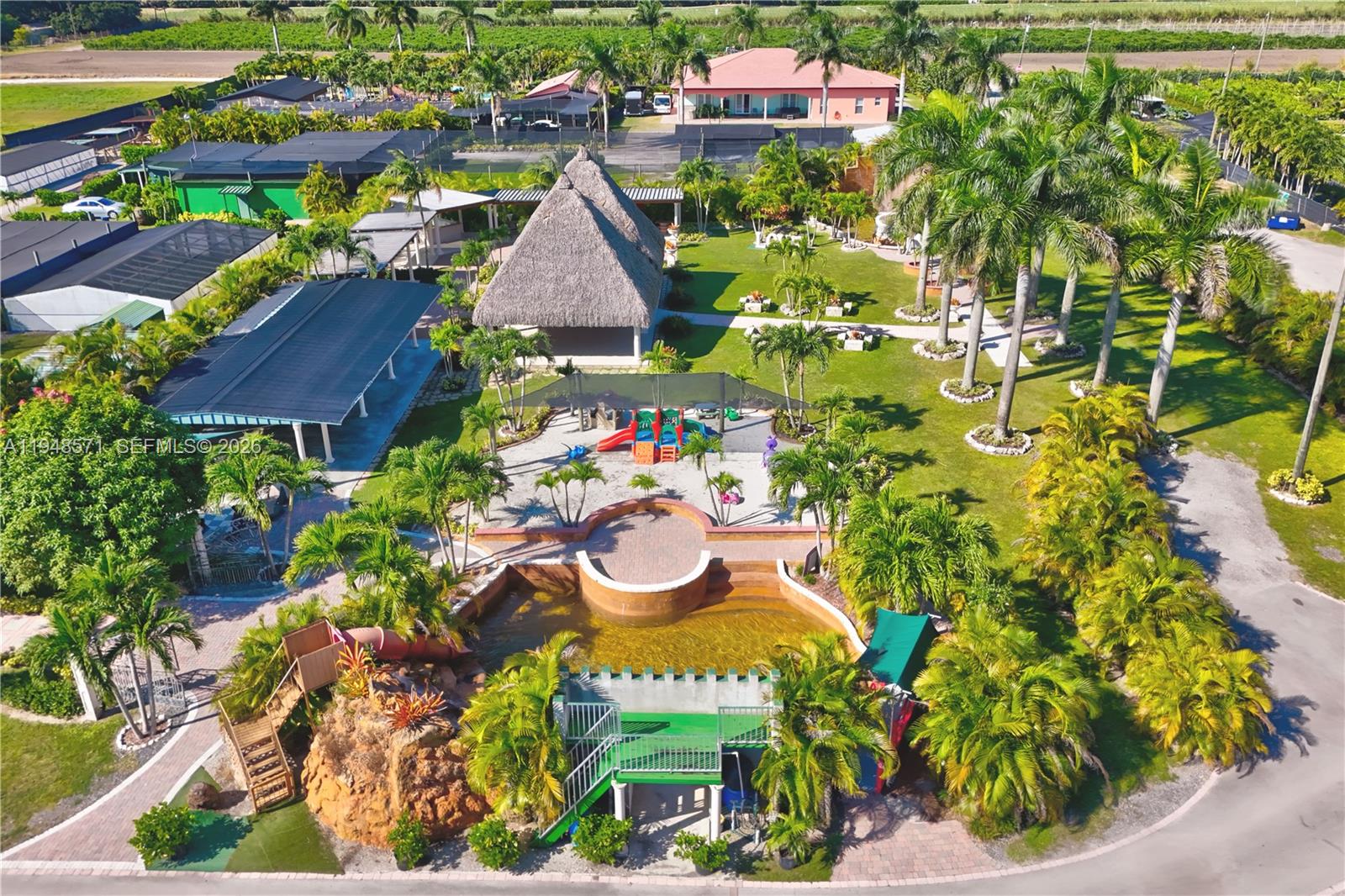 An aerial view shows a recreational area with a thatched-roof pavilion, playground, and pool — 20455 SW 154th Ave, Miami FL 33187, MIAMI, FL