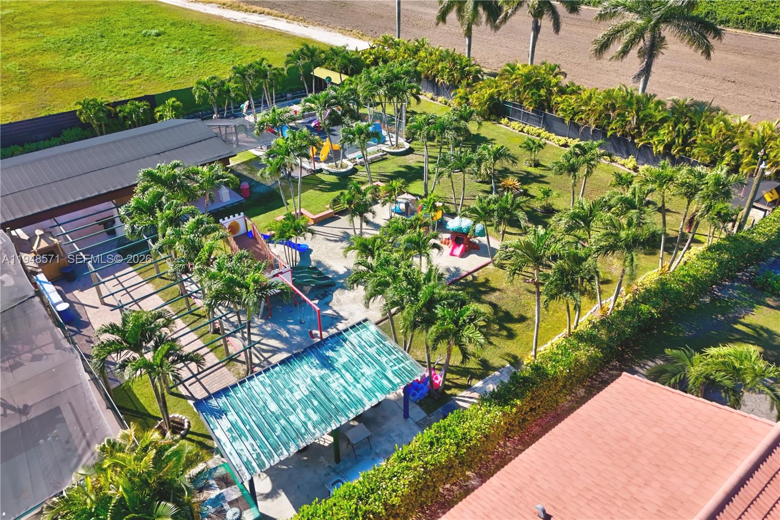An aerial view shows a large backyard with multiple playgrounds, palm trees, and covered patios — 20455 SW 154th Ave, Miami FL 33187, MIAMI, FL