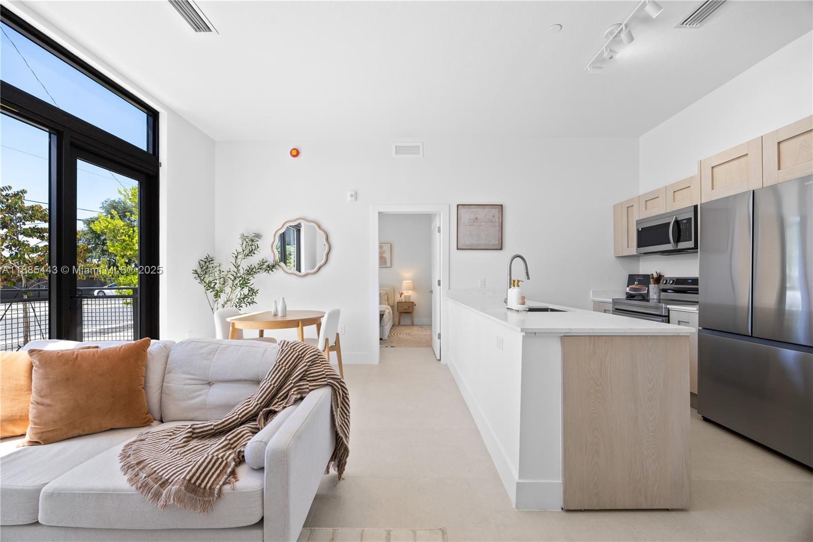 A modern open-concept living room and kitchen featuring light wood cabinetry and stainless steel appliances — 21850 Old Dixie highway # 001, Miami FL 33170, MIAMI, FL