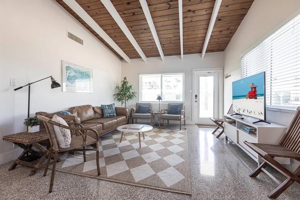 A living room with a wood-beamed ceiling, leather sofa, checkered rug, and tiled flooring — 6006 MIDNIGHT PASS ROAD UNIT 58, SARASOTA, FL