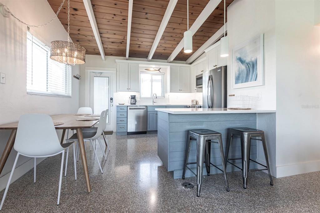 A kitchen and dining area with white cabinets, a blue island, and a wood-beamed ceiling — 6006 MIDNIGHT PASS ROAD UNIT 58, SARASOTA, FL