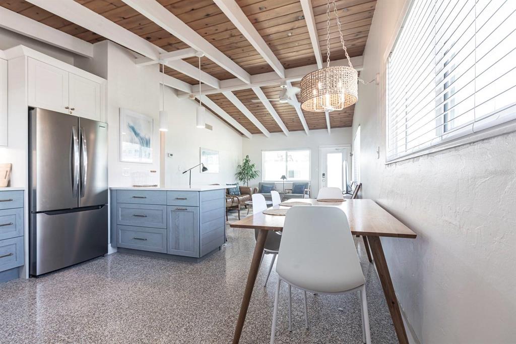 A kitchen and dining area features a wood-beamed ceiling, stainless steel refrigerator, and speckled flooring — 6006 MIDNIGHT PASS ROAD UNIT 58, SARASOTA, FL
