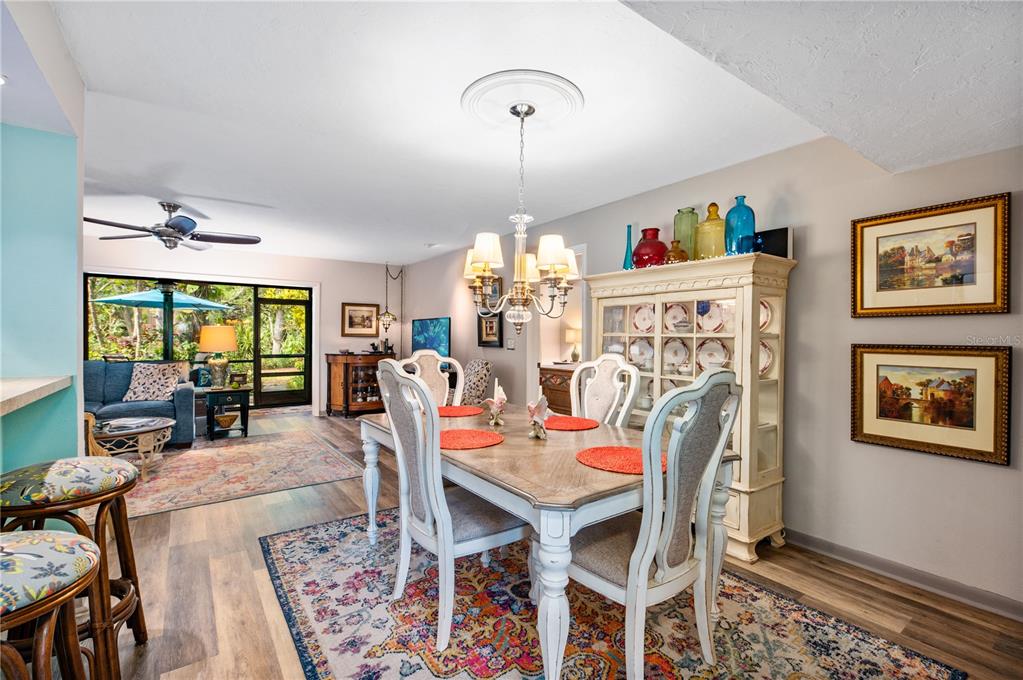 A dining area with a wooden table and chairs sits adjacent to a living room — 1701 PELICAN COVE ROAD UNIT 359, SARASOTA, FL
