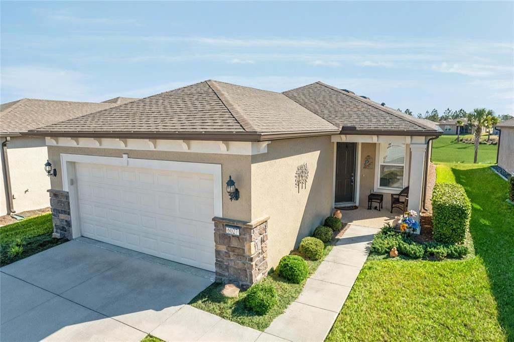 A single-story house with a tan stucco exterior, stone accents, and a two-car garage — 6027 SW 93RD CIRCLE, OCALA, FL