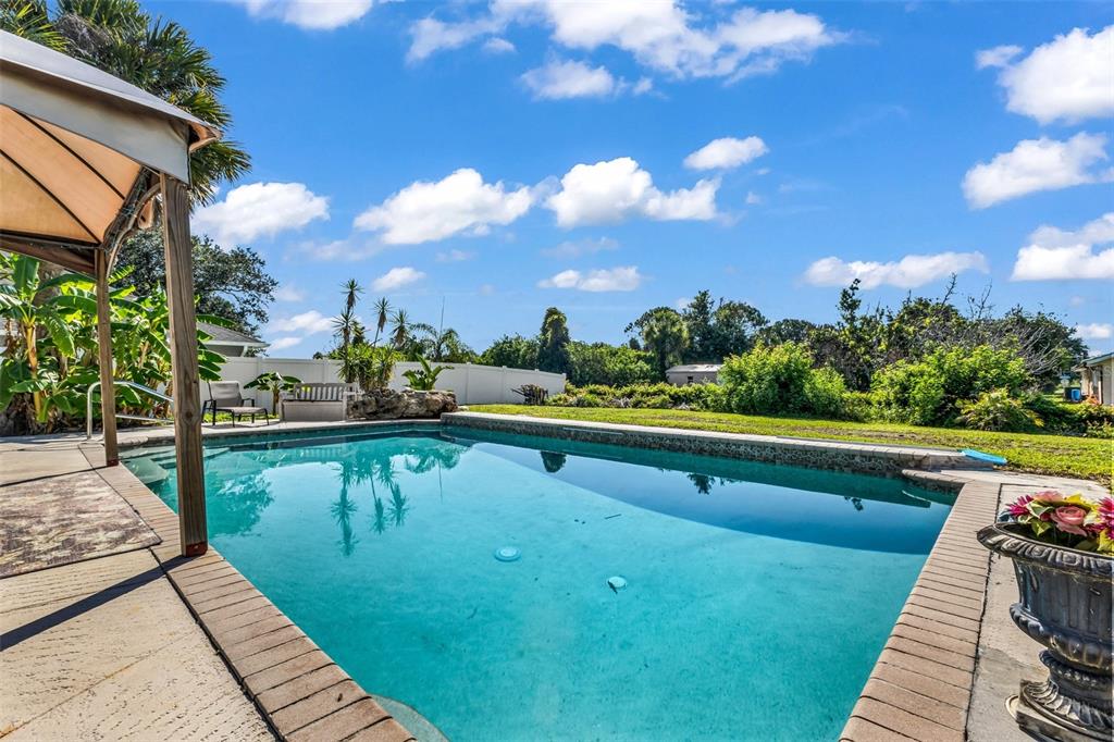 A backyard swimming pool with a gazebo and a white fence under a blue sky — 2210 EMBASSY ROAD, NORTH PORT, FL