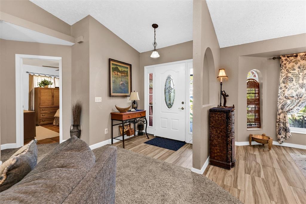 An entryway features a white front door, wood-look tile flooring, and a carpeted living area — 2210 EMBASSY ROAD, NORTH PORT, FL