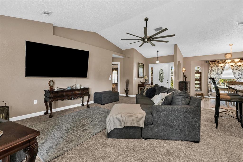 A living room features a large television, a gray sectional sofa, and a ceiling fan — 2210 EMBASSY ROAD, NORTH PORT, FL