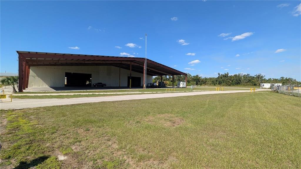 A large, open-sided metal hangar building sits on a grassy lot under a blue sky — 1509 S BYRON BUTLER PARKWAY, PERRY, FL
