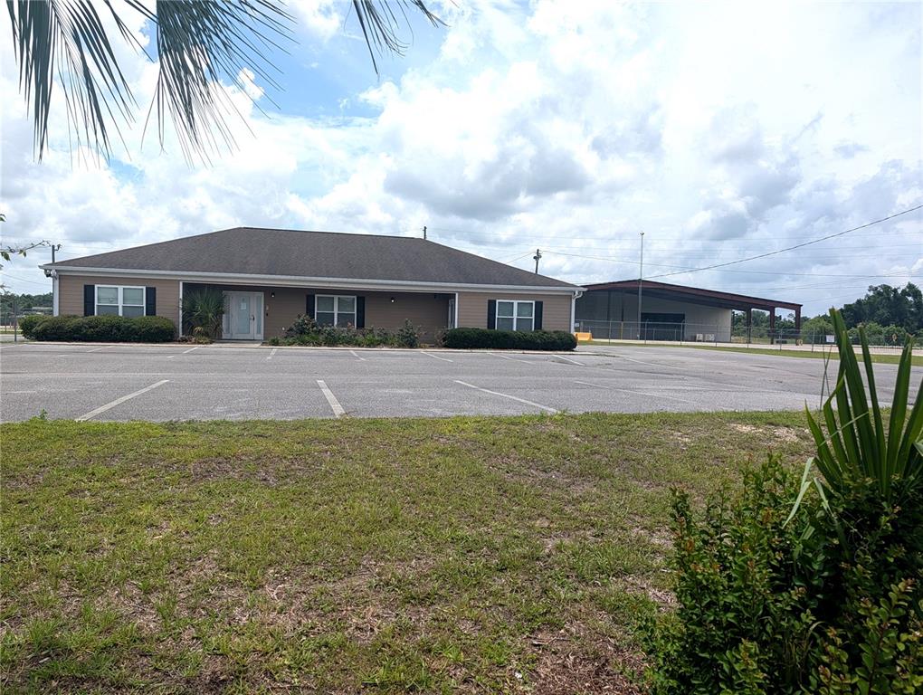 A single-story commercial building with a parking lot and an adjacent metal warehouse structure — 1509 S BYRON BUTLER PARKWAY, PERRY, FL