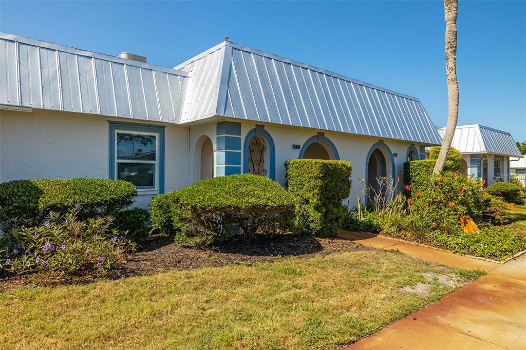 A single-story building with a white metal roof, arched entryways, and landscaped front yard — 4239 TAMARGO DRIVE, NEW PORT RICHEY, FL