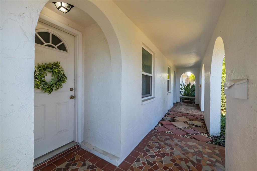 A white front door with a wreath sits under a covered arched entryway with tile — 4239 TAMARGO DRIVE, NEW PORT RICHEY, FL