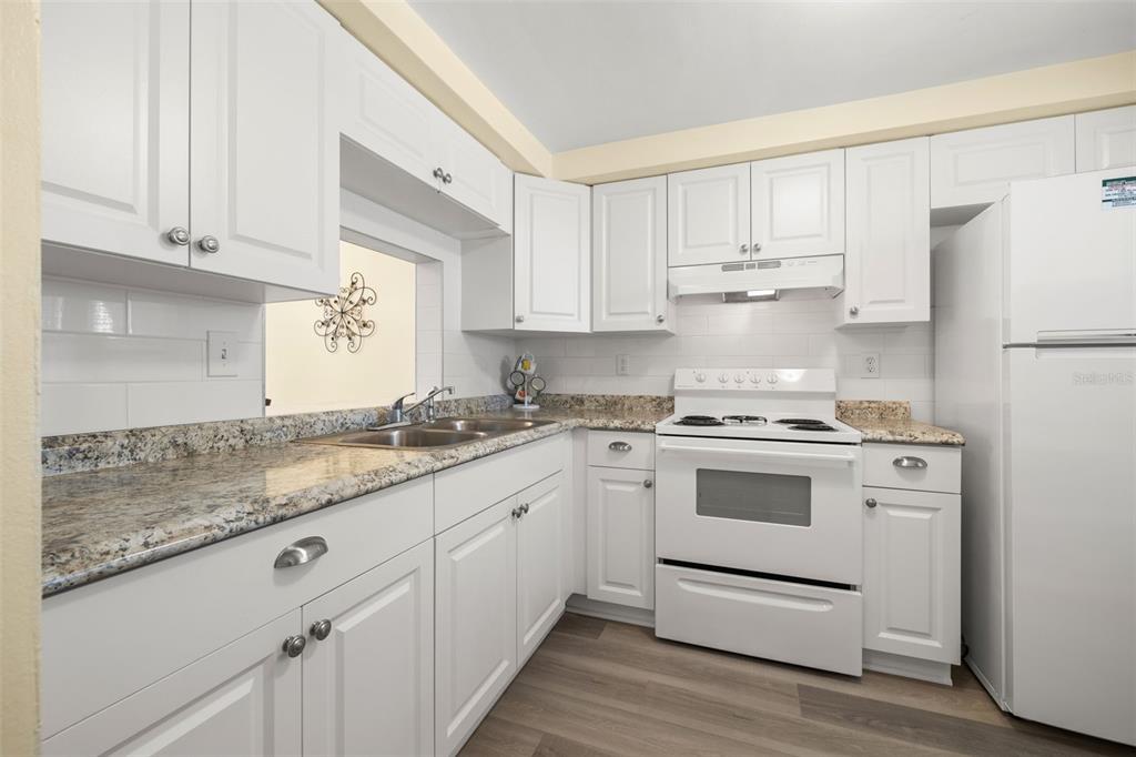 A kitchen features white cabinets, granite countertops, a white stove, and a white refrigerator — 4239 TAMARGO DRIVE, NEW PORT RICHEY, FL