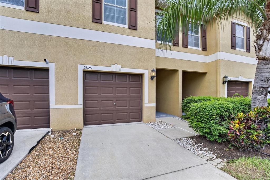 The exterior of a two-story townhouse features a brown garage door and a concrete driveway — 2829 SANTEGO BAY COURT, BRANDON, FL