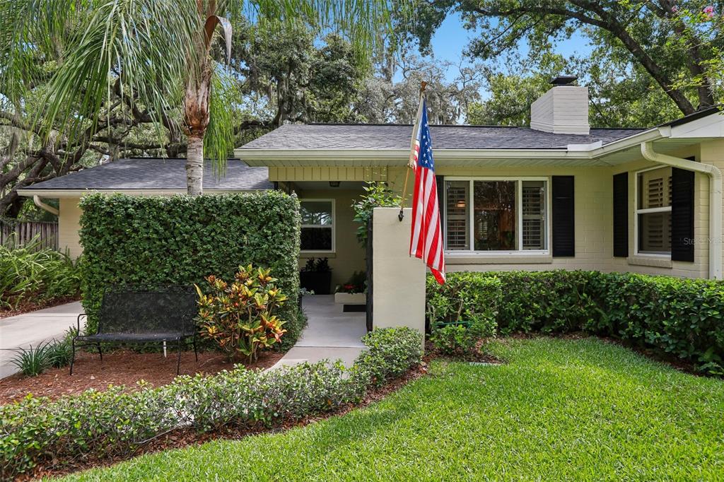 A single-story house with a brick exterior, a flag, and a landscaped front yard — 204 S BURLINGAME AVENUE, TEMPLE TERRACE, FL