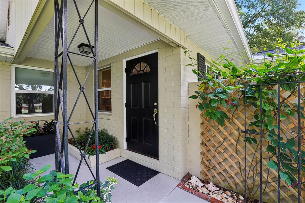 A black front door with a small arched window sits under a covered porch entrance — 204 S BURLINGAME AVENUE, TEMPLE TERRACE, FL