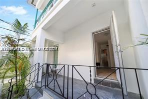 A covered balcony with a black metal railing overlooks a palm tree and yard — 820 15th St # 104, Miami Beach FL 33139, MIAMI BEACH, FL