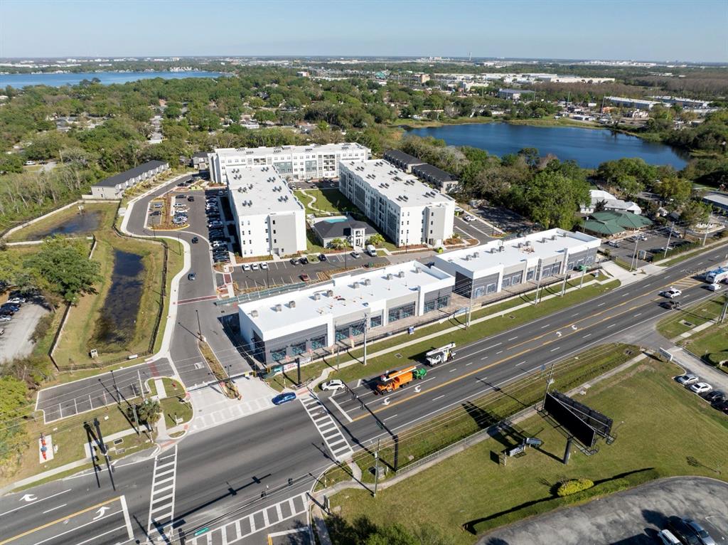 An aerial view shows a multi-story apartment complex with a commercial building and parking lot — 7813 S ORANGE AVENUE, ORLANDO, FL
