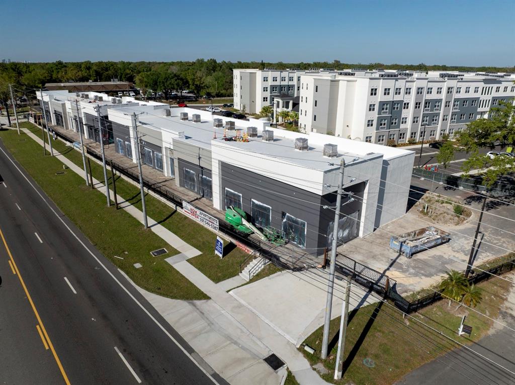 An aerial view shows a newly constructed commercial building next to a large apartment complex — 7813 S ORANGE AVENUE, ORLANDO, FL