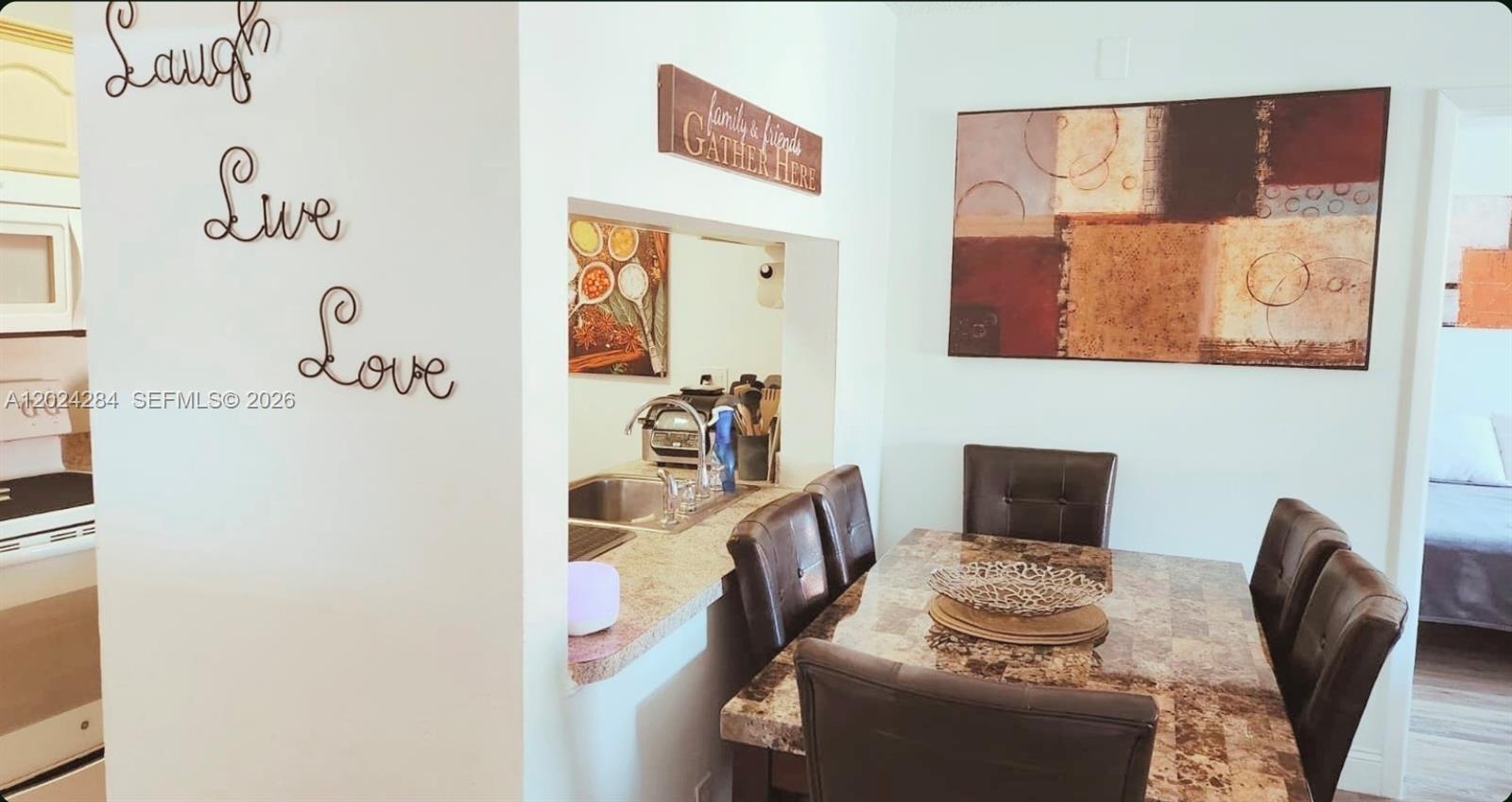 A dining area features a marble-topped table, dark leather chairs, and a kitchen pass-through window — 6480 W 27th Ct # 22, Hialeah FL 33016, HIALEAH, FL