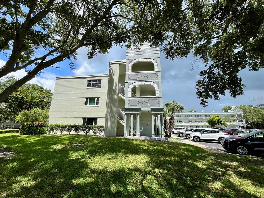 A three-story apartment building with a decorative stairwell tower and an adjacent parking lot — 2292 COSTA RICAN DRIVE UNIT 22, CLEARWATER, FL