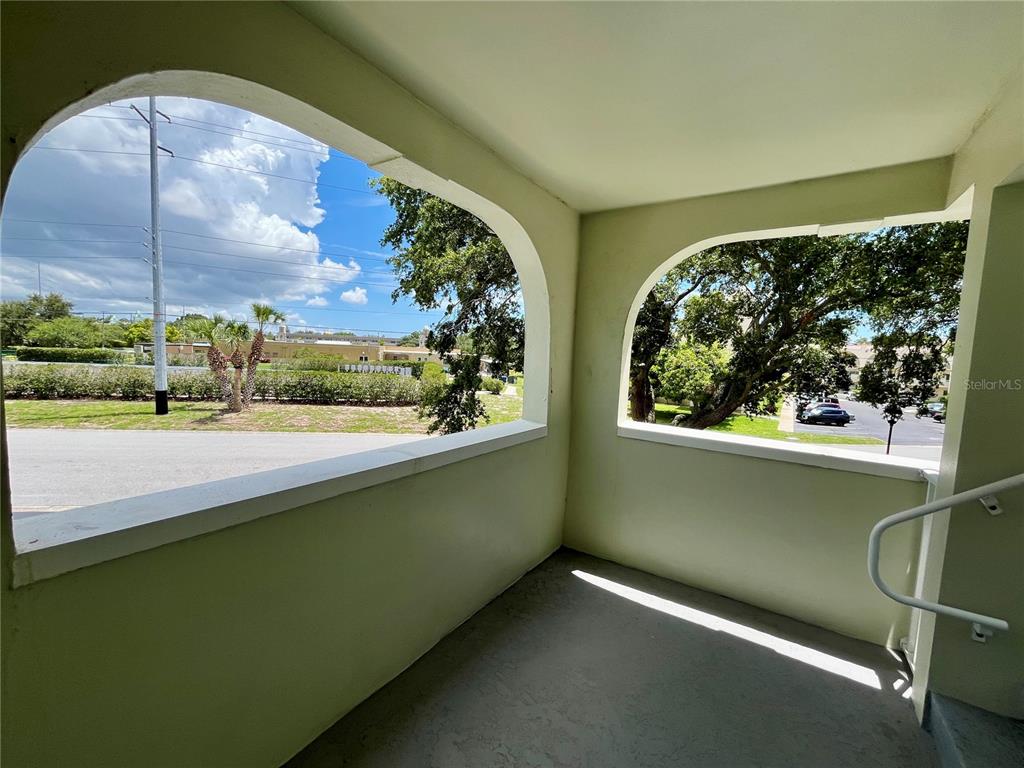 An outdoor covered balcony features arched openings, light green walls, and a gray floor — 2292 COSTA RICAN DRIVE UNIT 22, CLEARWATER, FL