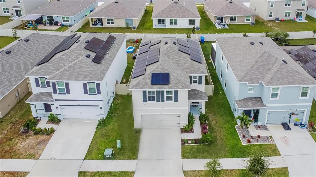 An aerial view shows three suburban houses with solar panels on their shingled roofs — 17029 BLISTER WING DRIVE, WIMAUMA, FL