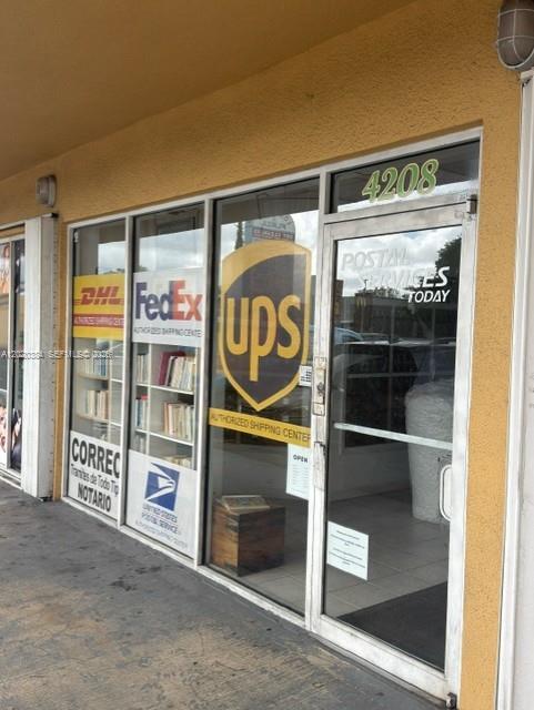 The exterior of a commercial storefront features glass doors and windows with shipping company signage — XXXX W 16th Ave, Hialeah FL 33012, HIALEAH, FL