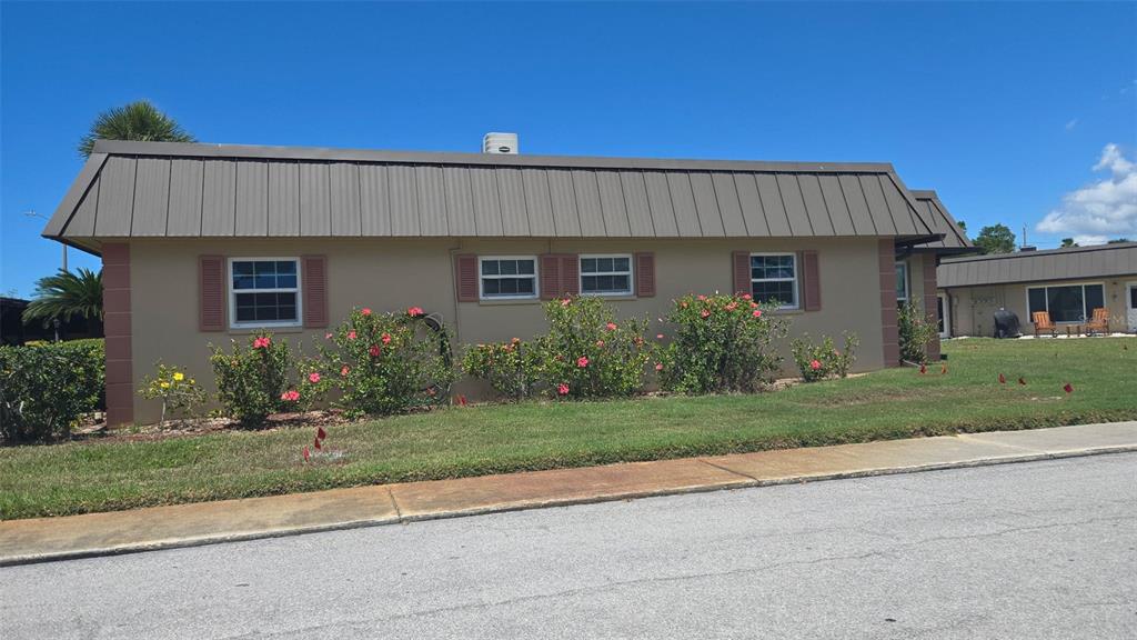 A tan, single-story building with a brown metal roof and red-shuttered windows — 4249 STRATFORD DRIVE UNIT 4249, NEW PORT RICHEY, FL