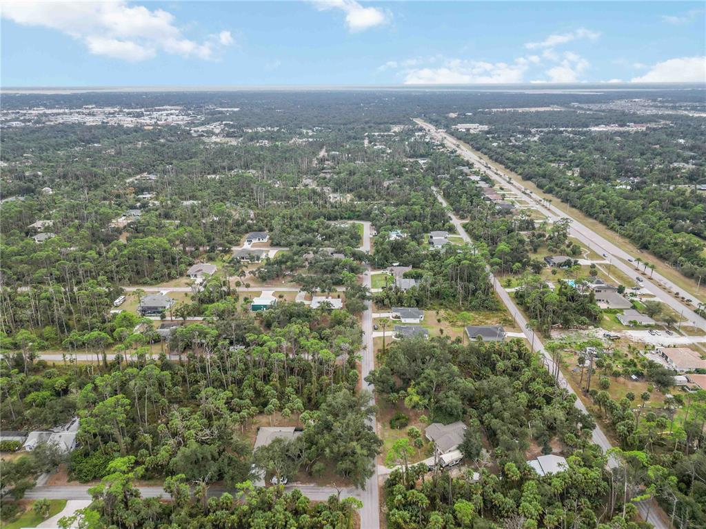 An aerial view shows a residential neighborhood with scattered houses surrounded by dense wooded areas — 17370 WELLSLEY AVENUE, PORT CHARLOTTE, FL