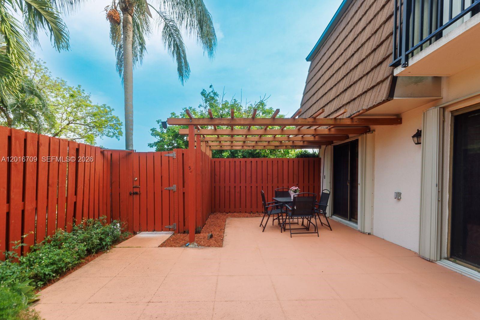 A patio features a wooden pergola, a red privacy fence, and a small dining set — 9126 SW 20th Pl # C, Davie FL 33324, DAVIE, FL
