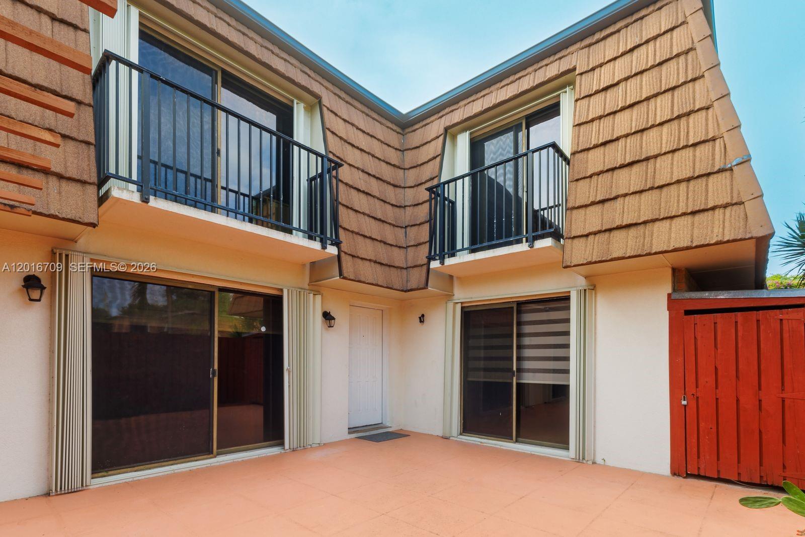 A two-story building exterior features a paved patio, sliding glass doors, and upper-level balconies — 9126 SW 20th Pl # C, Davie FL 33324, DAVIE, FL