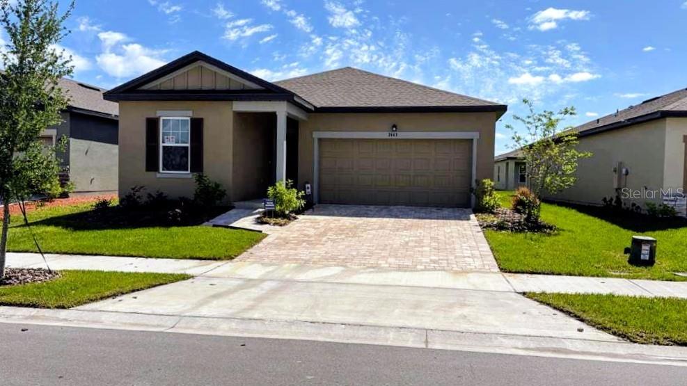 A single-story house with a tan exterior, a paved driveway, and a two-car garage — 2449 GREY HAWK DR, KISSIMMEE, FL