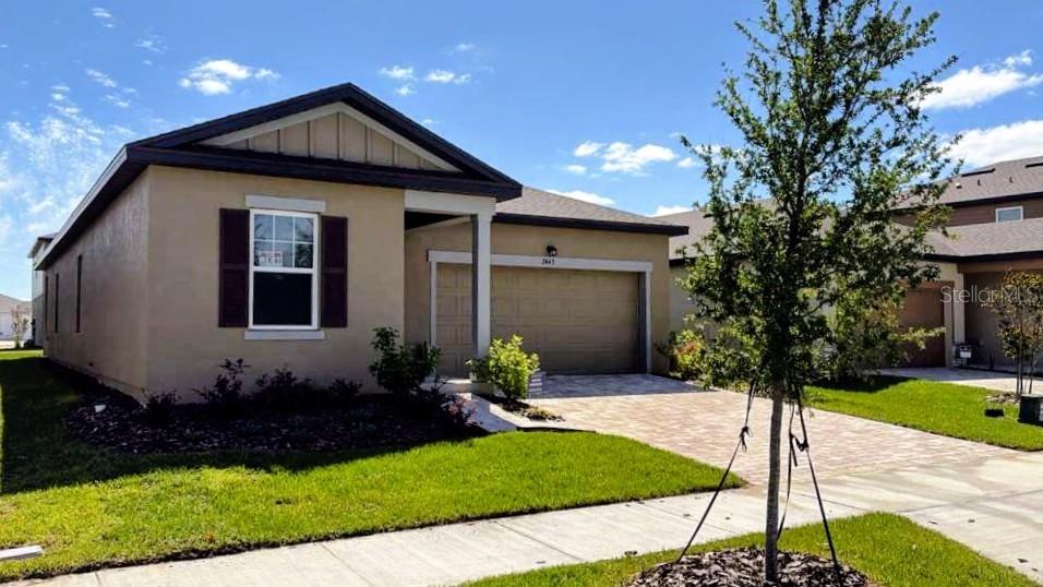 A single-story house with a tan stucco exterior, a two-car garage, and a paved driveway — 2449 GREY HAWK DR, KISSIMMEE, FL