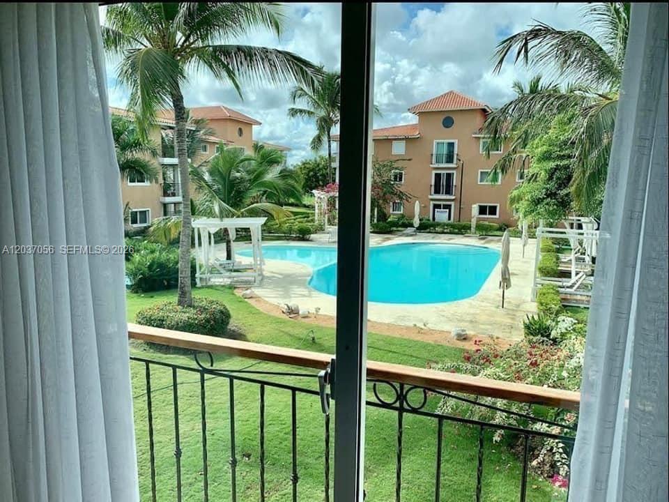 A view from a balcony overlooking a swimming pool surrounded by palm trees and buildings — 0 La cana # 0, FL