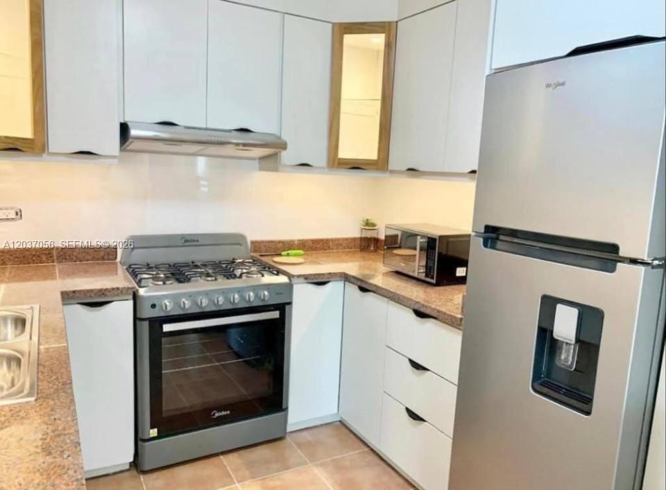 A kitchen features white cabinetry, granite countertops, a stainless steel stove, and a refrigerator — 0 La cana # 0, FL