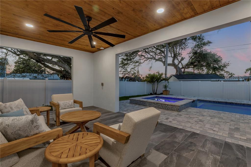 A covered patio with a wood ceiling and ceiling fan overlooks a pool and spa — 210 DUE EAST STREET, NEW SMYRNA BEACH, FL