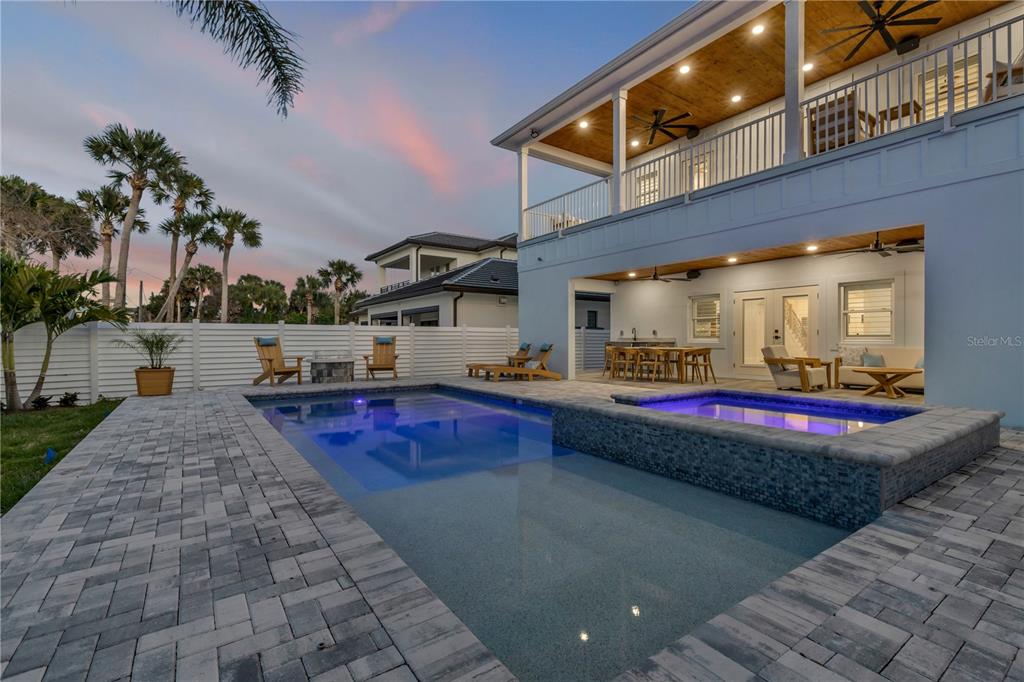 A backyard features a swimming pool, a raised spa, and a two-story house with balconies — 210 DUE EAST STREET, NEW SMYRNA BEACH, FL