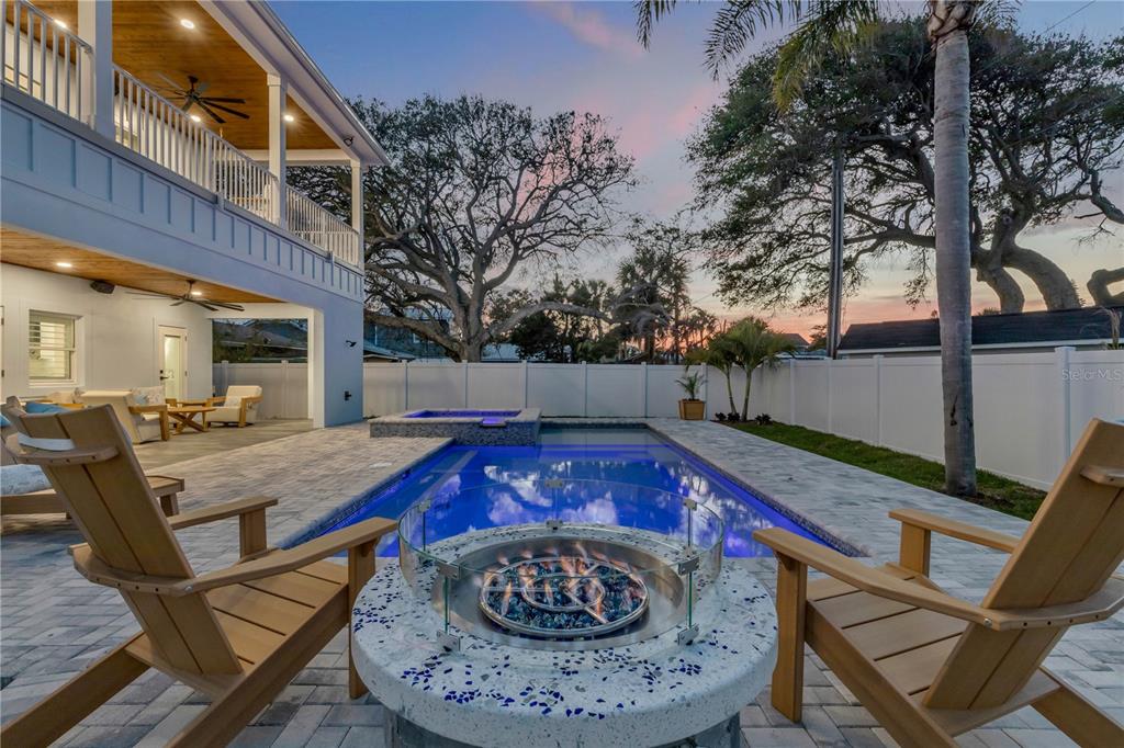 A backyard features a swimming pool, a fire pit with chairs, and a covered patio — 210 DUE EAST STREET, NEW SMYRNA BEACH, FL