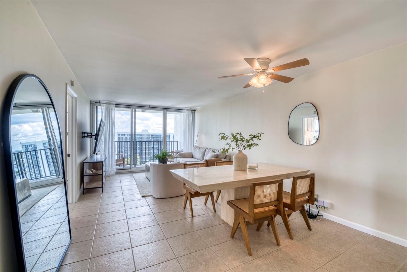 A dining area with a stone table and cane chairs sits before a living room balcony — 525 N Ocean Boulevard # 1215, Pompano Beach FL 33062, POMPANO BEACH, FL