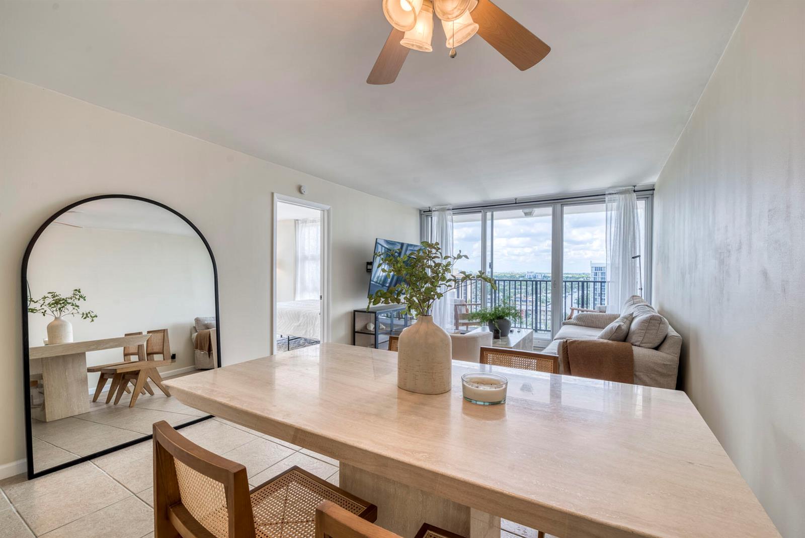 A dining area with a stone table and arched mirror opens into a living room — 525 N Ocean Boulevard # 1215, Pompano Beach FL 33062, POMPANO BEACH, FL