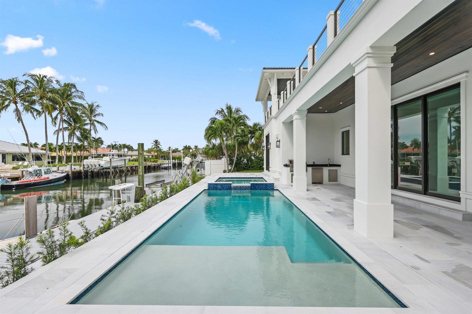 A modern house features a swimming pool, spa, and outdoor kitchen overlooking a canal — 1211 Gulfstream Way, Singer Island FL 33404, SINGER ISLAND, FL