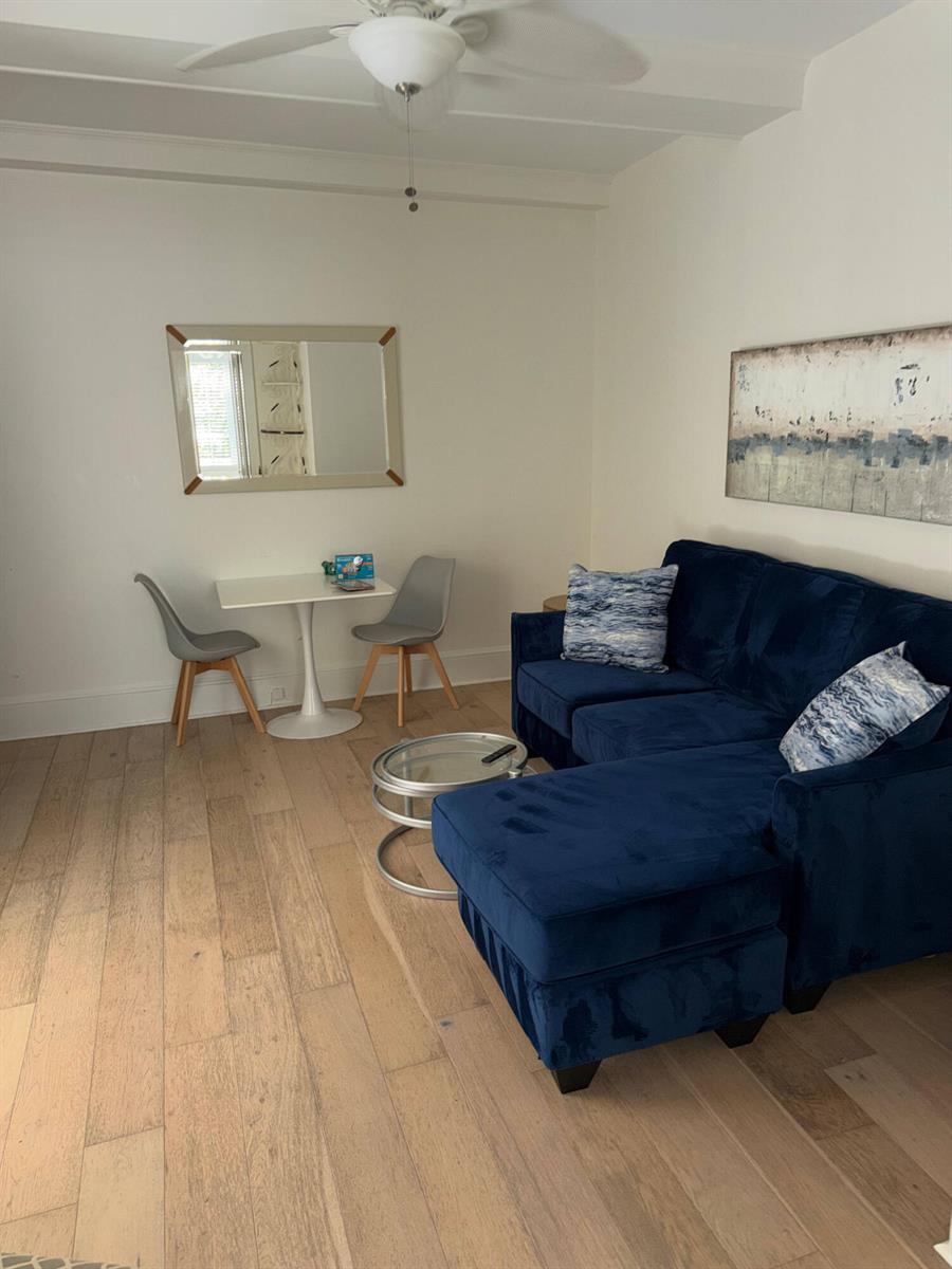 A living room features a blue sectional sofa, a small dining table, and hardwood floors — 301 Chilean Avenue # 0080, Palm Beach FL 33480, PALM BEACH, FL