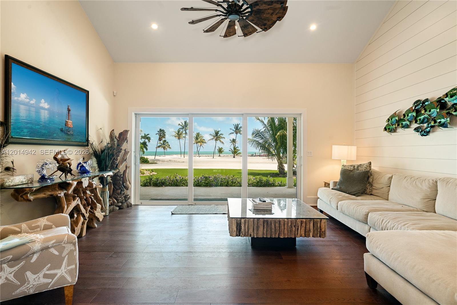 A living room features a large sliding glass door overlooking a beach and ocean view — 88835 Old Hwy, Tavernier FL 33070, TAVERNIER, FL