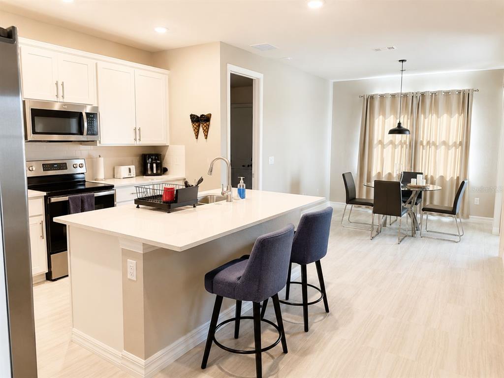 A kitchen with white cabinets, a quartz island, and a dining area with light flooring — 2635 BEBB OAK DRIVE, NORTH PORT, FL