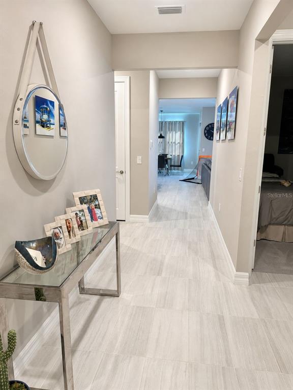 A hallway with light-colored tile flooring leads toward a dining area and living space — 2635 BEBB OAK DRIVE, NORTH PORT, FL