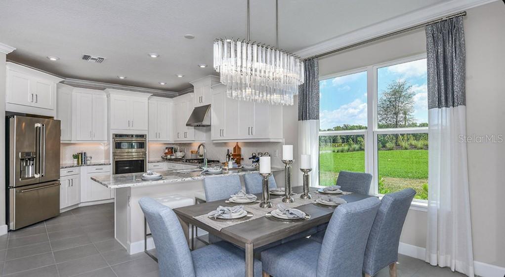A kitchen and dining area with white cabinets, stainless appliances, and a crystal chandelier — 7907 INTERSTELLAR AVENUE, SARASOTA, FL