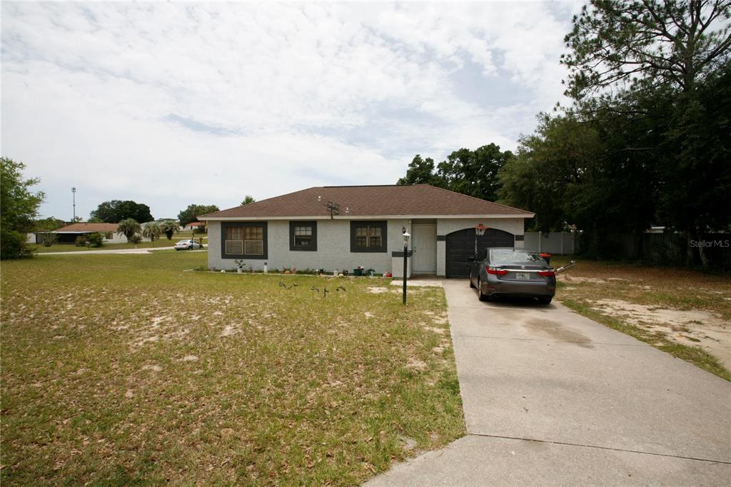 A single-story house with a gray stucco exterior, dark trim, and a concrete driveway — 314 OAK TRACK PASS, OCALA, FL