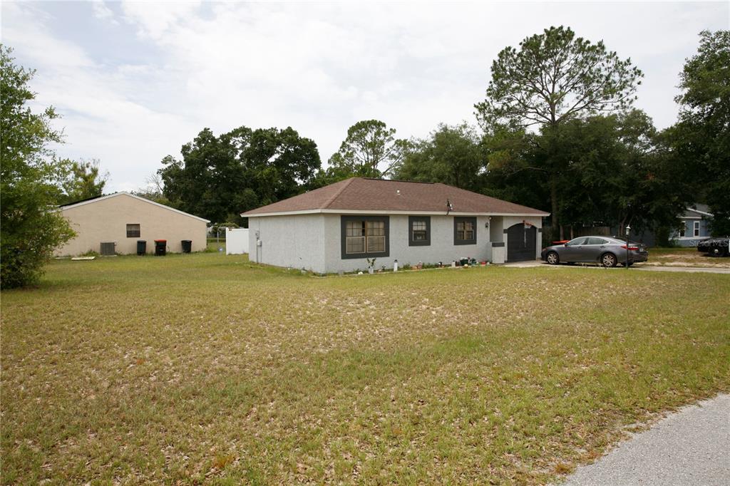 A single-story house with a stucco exterior and a brown roof sits on a lot — 314 OAK TRACK PASS, OCALA, FL