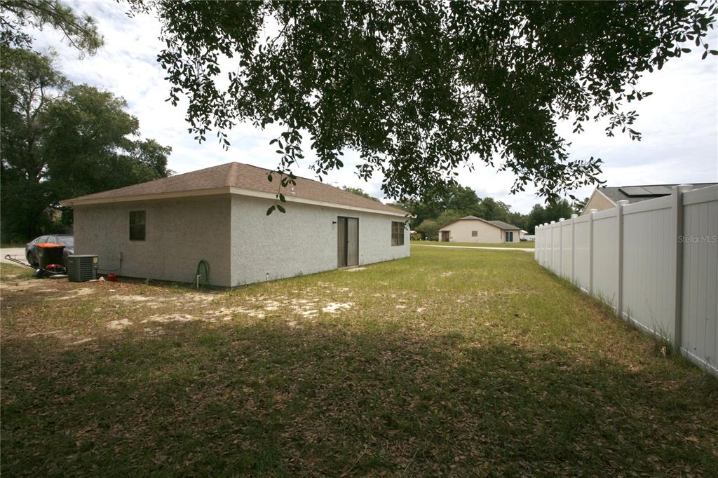 A view of the side of a house with a white vinyl fence and yard — 314 OAK TRACK PASS, OCALA, FL