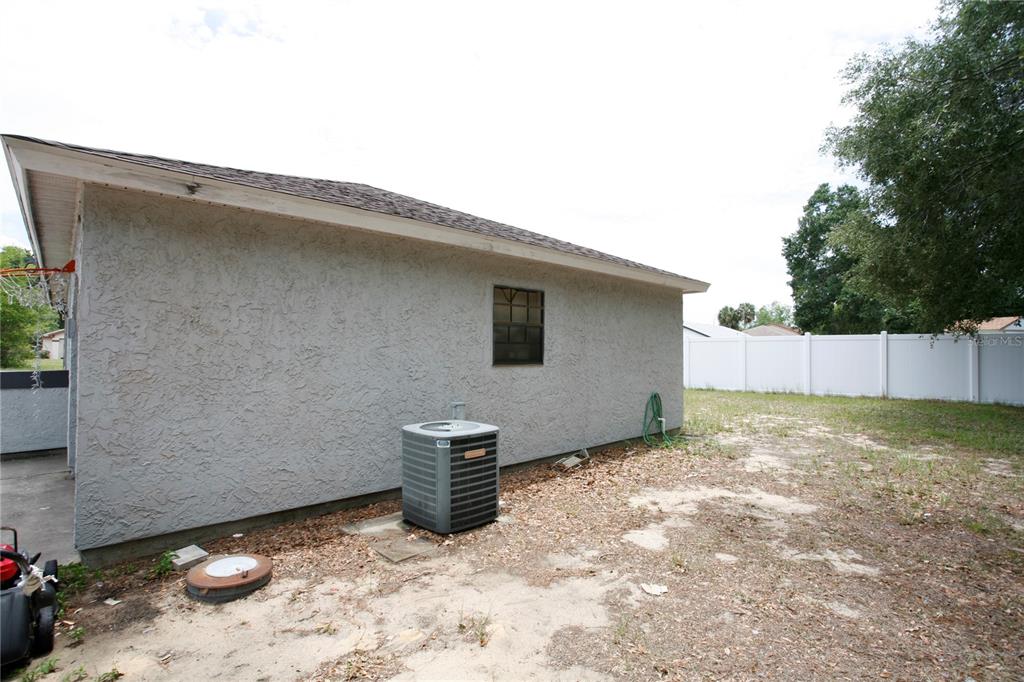 The exterior of a house features a stucco wall, an air conditioning unit, and a window — 314 OAK TRACK PASS, OCALA, FL